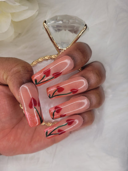 Hand with floral nail art holding a clear nail file on a white background